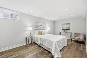 Lower-level bedroom with sitting area, modern flooring, and above-grade window.
