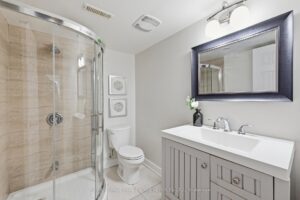 Modern lower-level bathroom with glass shower, vanity, and contemporary tile.