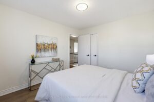 Bright bedroom with neutral décor, closet doors, and large window.