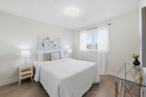 Secondary bedroom with large window, soft neutral finishes, and natural light.