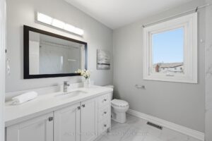 Four-piece bathroom with vanity, toilet, and bright window.