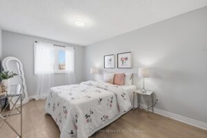 Bright bedroom with large window, modern flooring, and soft neutral finishes.