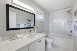 Bathroom with extended vanity, mirror, and tub-shower combination.
