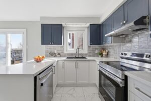 Modern kitchen with stainless steel appliances, tile backsplash, and two-tone cabinetry.