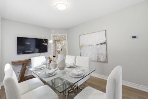 Formal dining room with modern table setting and wall-mounted TV.