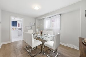 Dining area with large window, modern table, and view toward the kitchen.