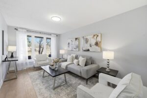 Bright living room with large windows, neutral décor, and double-door entry.