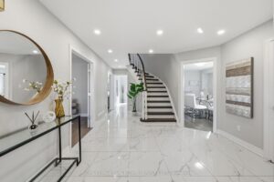 Grand foyer with polished tile flooring, curved staircase, and elegant console table.