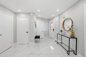 Front foyer with double closet doors, polished tile flooring, and staircase view.