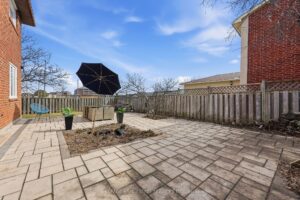 Rear exterior of the detached brick home with spacious backyard and patio.