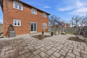 Spacious interlock backyard patio with brick exterior, fencing, and outdoor entertaining space.