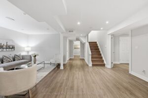 Finished basement recreation room with open layout, modern flooring, and staircase.