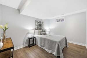 Lower-level bedroom with modern flooring, neutral décor, and above-grade window.