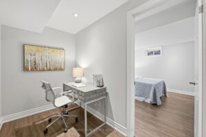 Lower-level office area with desk, modern flooring, and adjoining bedroom.