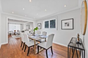 Formal dining room with hardwood flooring, modern seating, and view toward the living room.