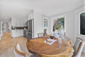 Open-concept kitchen and breakfast area with white cabinetry and large windows.