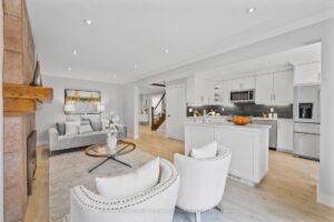 Open-concept family room and kitchen with brick fireplace and white cabinetry.