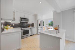 Modern kitchen with white cabinetry, stainless steel appliances, and peninsula seating.