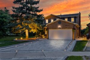 Twilight front elevation of the detached home with double garage and landscaped driveway.