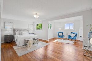 Spacious primary bedroom with hardwood flooring, sitting area, and large windows.