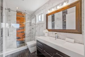 Spa-inspired bathroom with double vanity, glass shower, and marble-look tile.