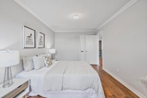 Secondary bedroom with hardwood flooring, neutral bedding, and spacious layout.