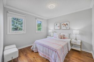 Bedroom with hardwood flooring, large windows, and soft pink accents.