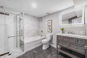 Modern basement bathroom with glass shower, vanity, and bathtub.