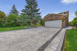 Front exterior of the detached brick home with wide patterned driveway and double garage.