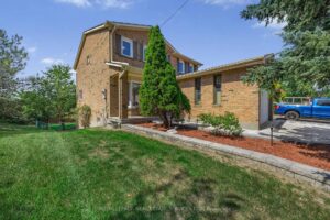 Front elevation of the detached home with landscaped lawn, mature trees, and brick exterior.