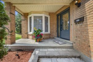 Covered front porch with double-door entry, brick exterior, and stone walkway.