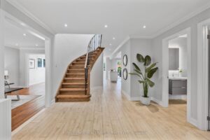 Bright front foyer with curved staircase, light wood flooring, and open-concept entry.