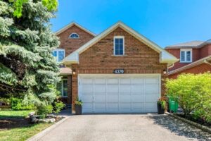 Front elevation of a two-storey detached brick home with attached garage and landscaped front yard.