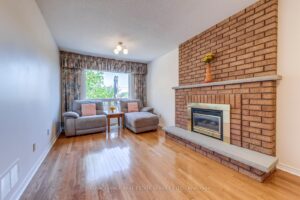 Bright family room featuring a brick fireplace, hardwood flooring, and comfortable seating area.