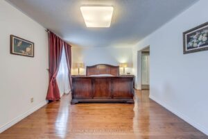 Spacious primary bedroom with hardwood flooring, large window, and traditional furnishings.