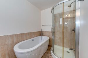 Primary ensuite bathroom with freestanding soaker tub, glass shower, and modern finishes.