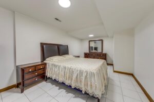 Finished basement bedroom with above-grade window, tile flooring, and neutral décor.