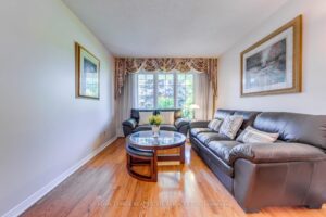 Bright living room with hardwood flooring, large front window, and comfortable seating.