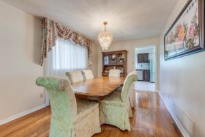 Formal dining room with hardwood flooring, elegant chandelier, and front window.