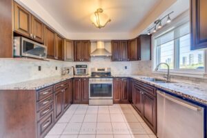 Bright kitchen with granite countertops, stainless steel appliances, and ample wood cabinetry.