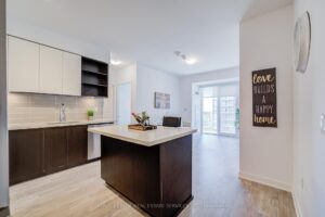 Open-concept kitchen with centre island, two-tone cabinetry, and balcony view beyond.