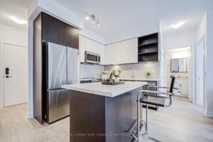 Kitchen with stainless steel fridge, centre island seating, and two-tone cabinetry.