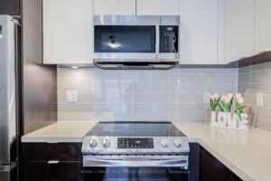Close-up of stainless steel range with tile backsplash and modern cabinetry.