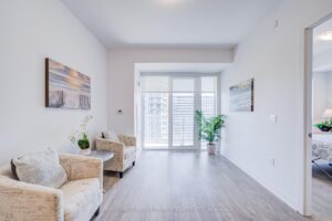 Living room with balcony doors, modern seating, and soft neutral finishes.