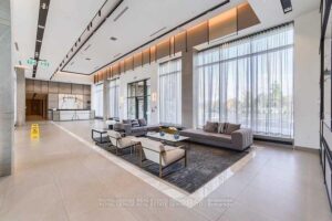 Elegant condominium lobby with floor-to-ceiling windows, lounge seating, and contemporary finishes.