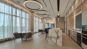 Resident lounge and kitchen area with modern cabinetry, seating, and circular ceiling lights.