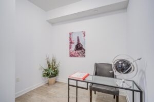 Den or home office area with light flooring, accent chair, and decorative wall art.