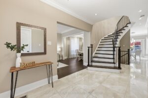 Bright front foyer with porcelain tile flooring, elegant staircase, and double-door entry.