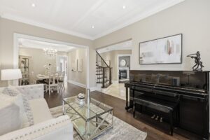 Formal living room with piano, hardwood flooring, and open view toward the dining room.