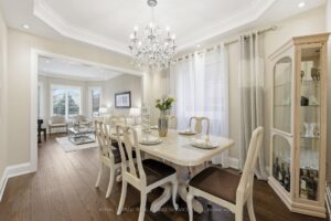Formal dining room with chandelier, hardwood flooring, and large windows overlooking the backyard.